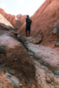 Rear view of man walking on rock in mountains