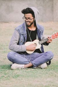 Young man playing guitar on field