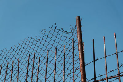 Low angle view of barbed wire fence against clear sky