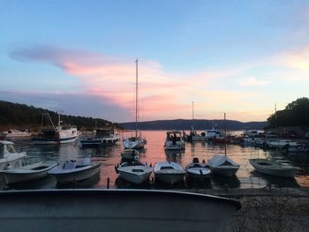 Boats moored at harbor against sky during sunset