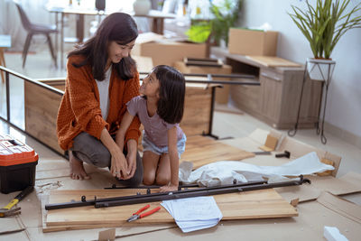 Mother and daughter assembling furniture at home