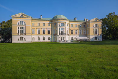 Lawn by building against blue sky