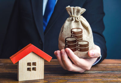 Midsection of businessman holding model house