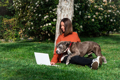 Woman using laptop with dog at park