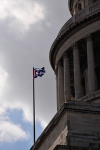 Low angle view of cuban flag by historic building against sky