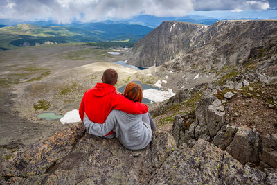 Rear view of couple sitting on rock