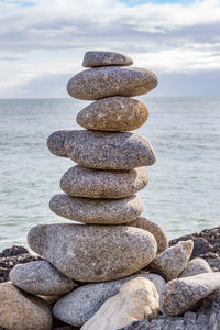 Stack of stones in sea against sky