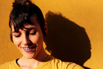 Close-up portrait of smiling mid adult woman against wall