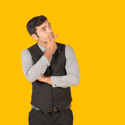 Young man looking away against yellow background