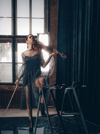 Woman with violin standing in home