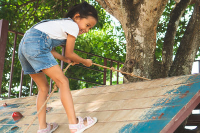 Full length of girl climbing on wood in park