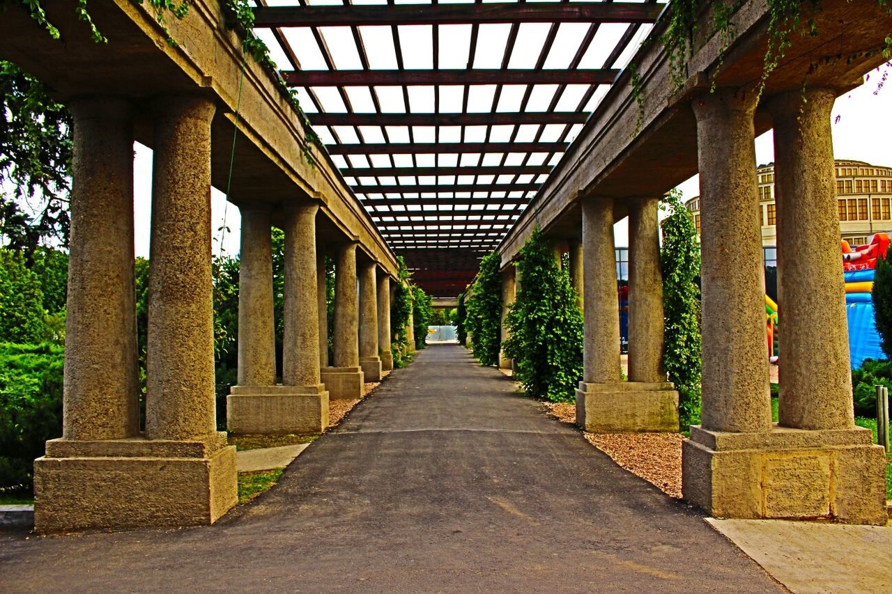 architecture, built structure, architectural column, the way forward, diminishing perspective, column, building exterior, colonnade, in a row, vanishing point, history, long, pillar, bridge - man made structure, travel destinations, incidental people, transportation, tree, day, walkway