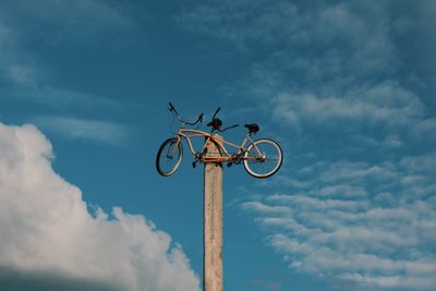 Low angle view of bicycle on pole against sky