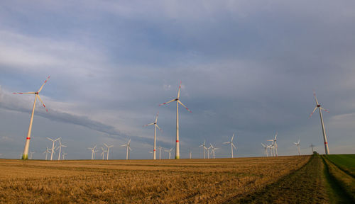 Wind turbines on field against sky