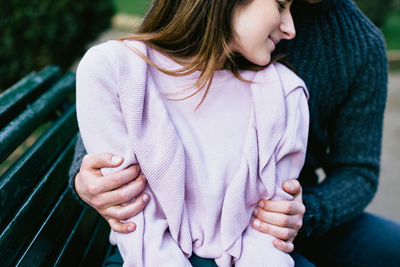 Midsection of couple romancing on park bench