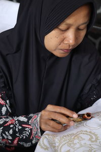 Close-up of woman doing embroidery on white fabric