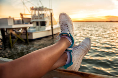 Low section of person on boat at sea during sunset