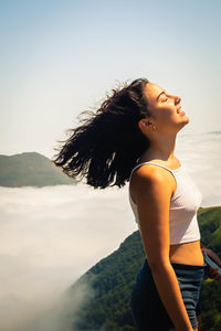 Teenage girl with eyes closed standing against sky