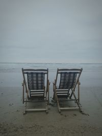 Deck chairs on beach against clear sky