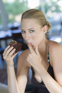 Woman eating dessert while sitting at table in cafe