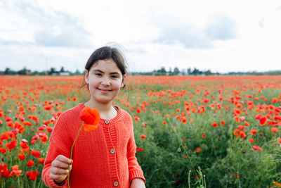Portrait of young woman standing amidst yellow flowering plants on field