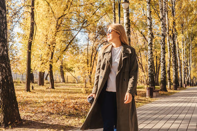 Woman standing against trees in park during autumn