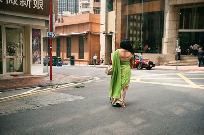 Rear view of woman walking while wearing sari on street in city