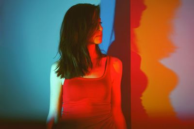 Close-up of young woman standing against red wall