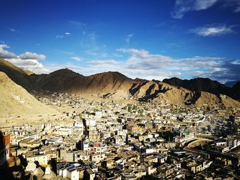 Aerial view of town by mountains against sky