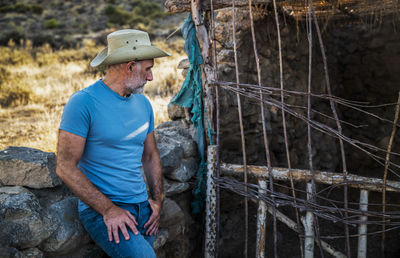 Adult man in cowboy hat and jean in a rural area