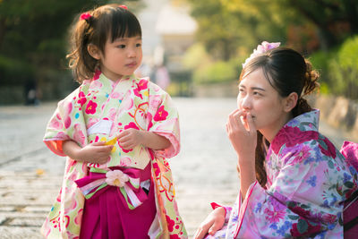 Mother and daughter wearing traditional clothing in park