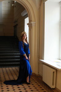 Full length portrait of teenage girl wearing royal blue dress standing at palace