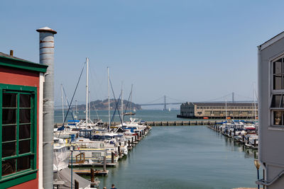 Sailboats moored at harbor against clear sky