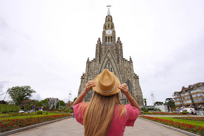 Rear view of woman standing against historic building