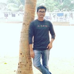 Portrait of young man standing against tree