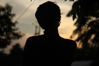 Rear view of silhouette man standing against sky during sunset