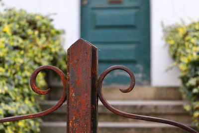 Close-up of rusty metal gate against building