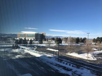 Snow covered road by buildings against sky