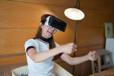 Happy woman enjoying while playing games on virtual reality headset