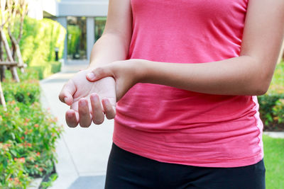 Midsection of woman with pain in wrist standing at park