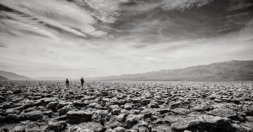 Mid distance of people walking on landscape against sky