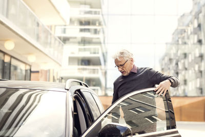 Senior man disembarking from car in city