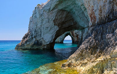 Rock formation in sea against blue sky