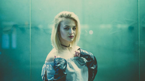 Close-up of young woman standing against wall