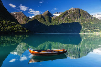 Boat on lake by mountains against sky