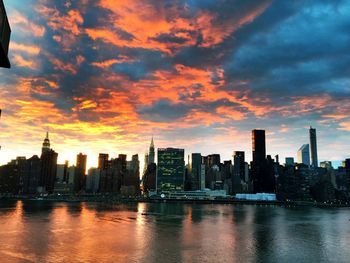 Cityscape by river against sky