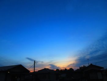 Silhouette houses against blue sky during sunset