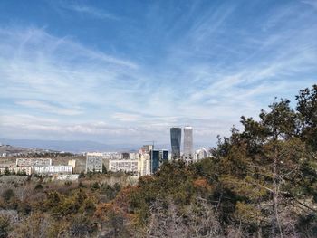 Buildings and trees against blue sky