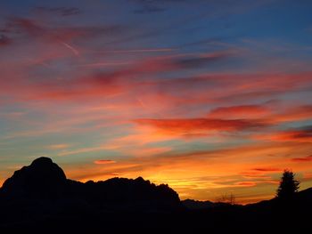 Low angle view of silhouette mountains against orange sky