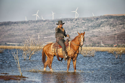 Portrait of men aiming gun riding horse in lake